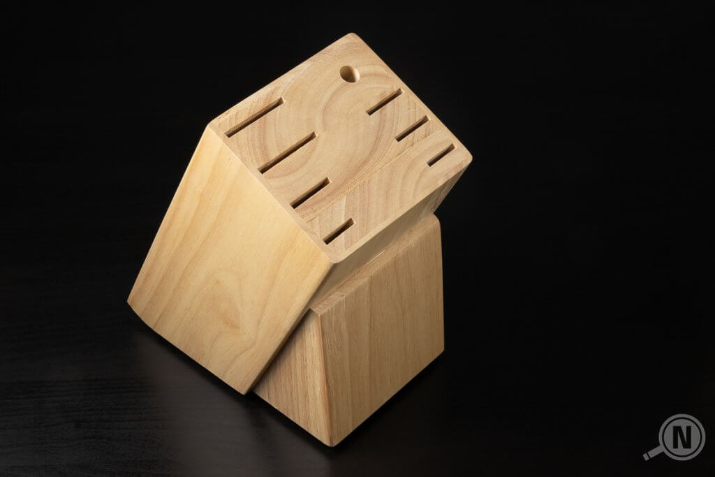 Leerer Messerblock aus Holz vor schwarzem Hintergrund.