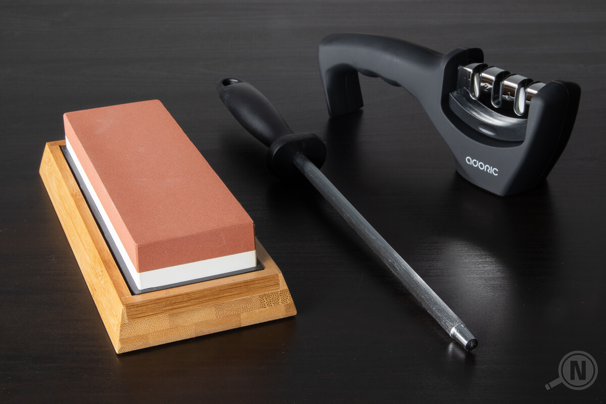 Schleifstein, Wetzstahl und Durchziehschleifer nebeneinander auf einer schwarzen Tischplatte