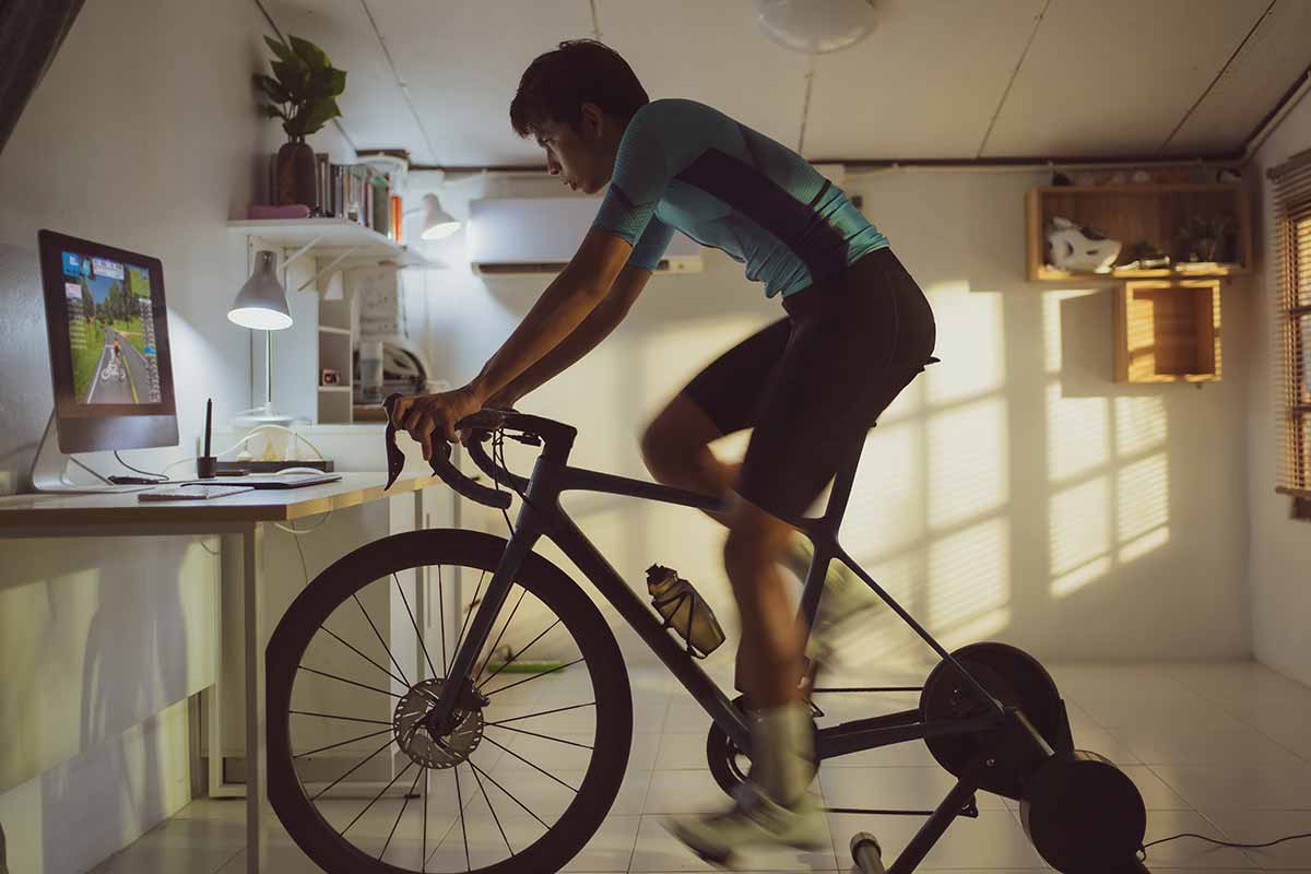 mann trainiert mit fahrrad-rollentraine rund schaut auf einen bildschirm