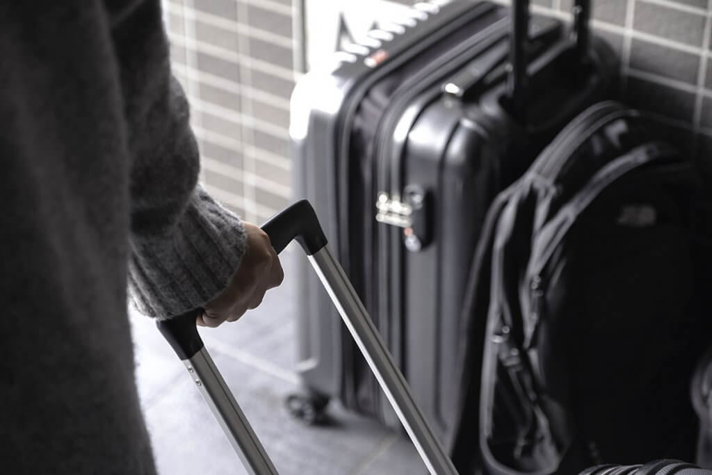 hartschalenkoffer-frau_zieht_koffer_hinter_sich_her-nahaufnahme-koffer_im_hintergund