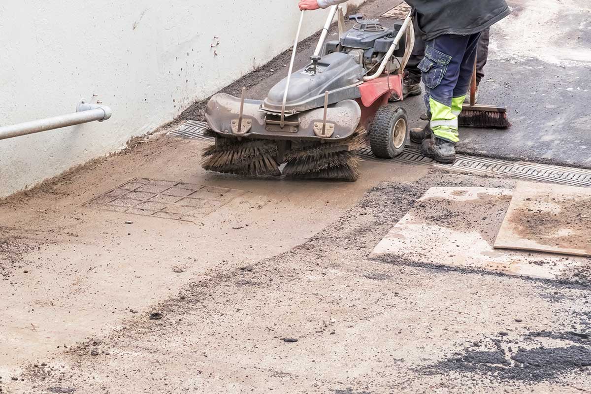 Handkehrer reinigt Straße