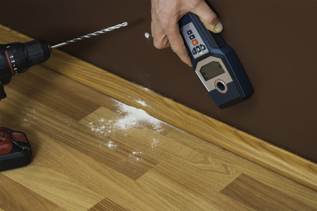 Mann mit Akkubohrer und Leitungssucher