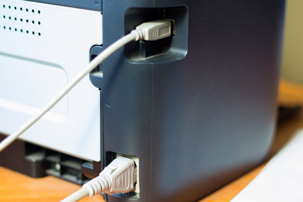 druckerrĂŒckseite mit sichtbarem strom- und lan-kabel