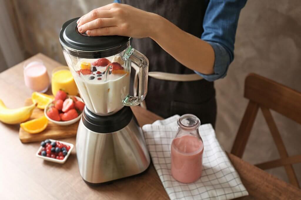 Person bereitet Smoothie in einem Mixer zu